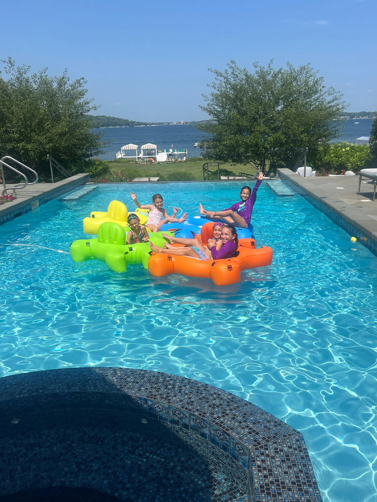 Kids in connected Fluzzle Tube pool floats having fun in the summer.