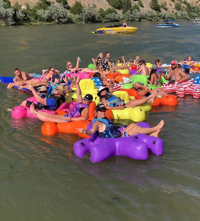 Group of friends on a water float with colorful puzzle shaped Fluzzle Tubes