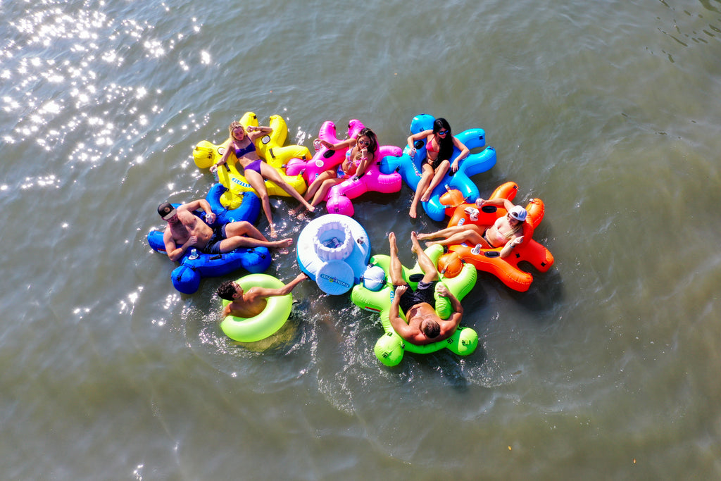A group of people floating on different color interlocking Fluzzle Tubes on a river. 