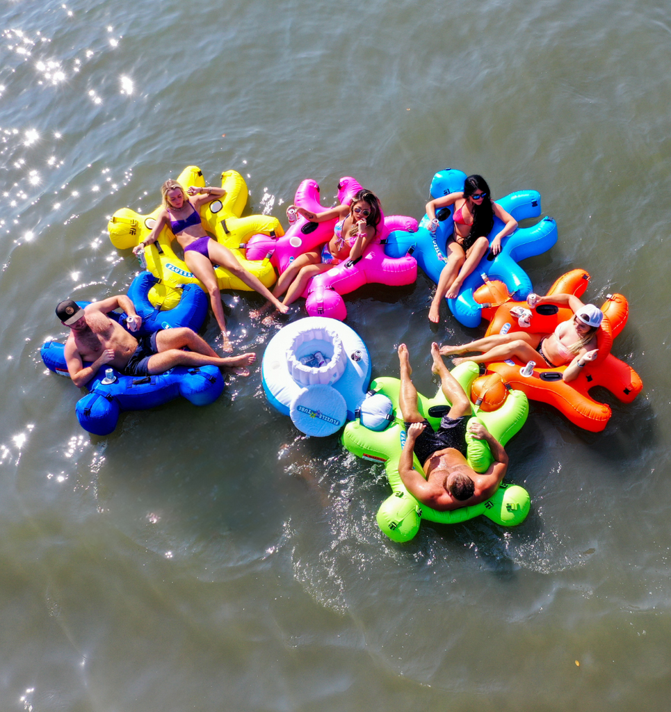 Group of friends floating on Interlocking Fluzzle Tubes in bright colors and an interlocking floating cooler. 