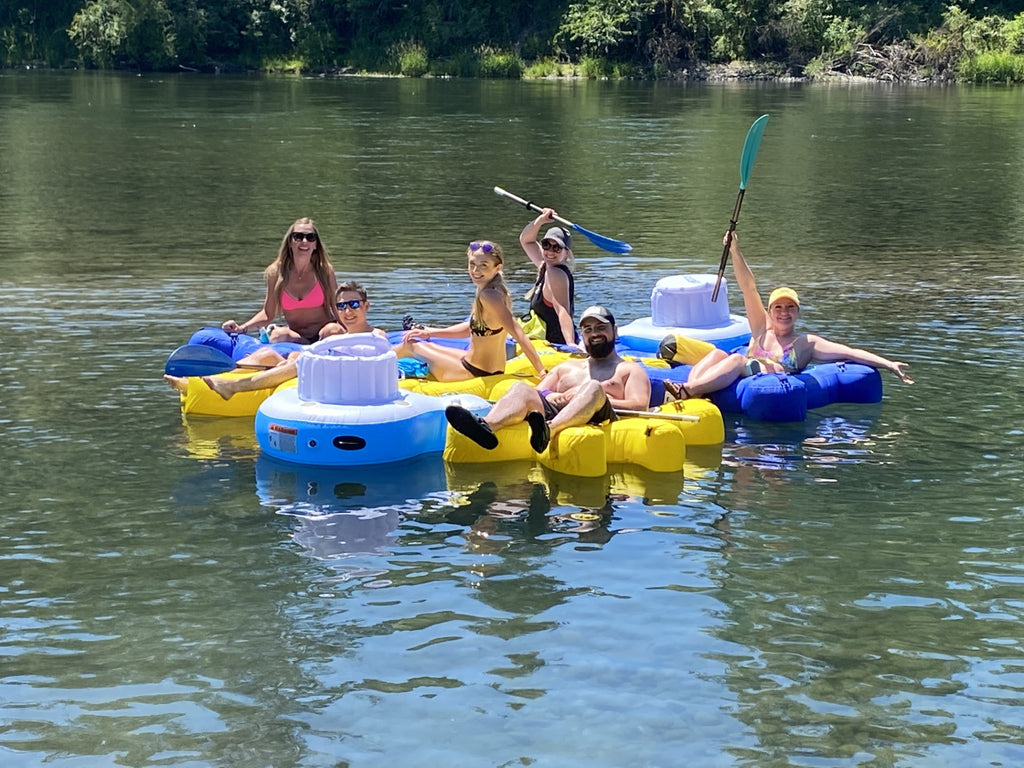 Family floating on a river in interlocking Fluzzle Tubes with an interlocking floating Fluzzle Tube cooler for their drinks. 