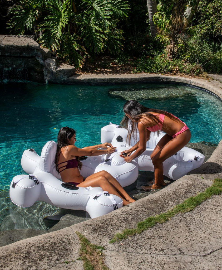 2 ladies in bikinis connecting 2 Fluzzle Tubes on the water.  