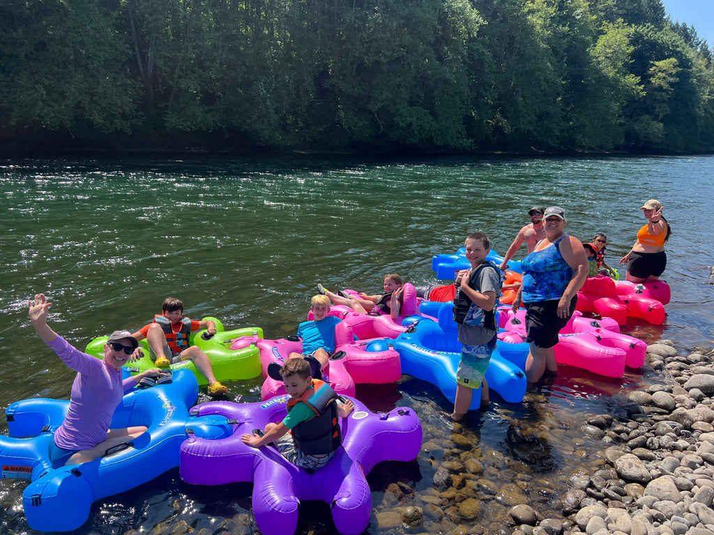 Family river floating with Fluzzle Tubes.  Puzzle shaped inflatable interlocking tubes for rivers, lakes or pools. Bright colors, mesh bottoms, back rests, expandable cup holders.  Interlocking floating cooler.
