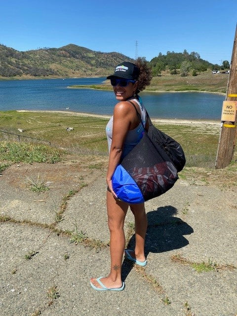 Woman carrying a Fluzzle Tube in a breathable mesh bag.  Storage and carrying back for Fluzzle Tube puzzle shaped interlocking float tubes. 
