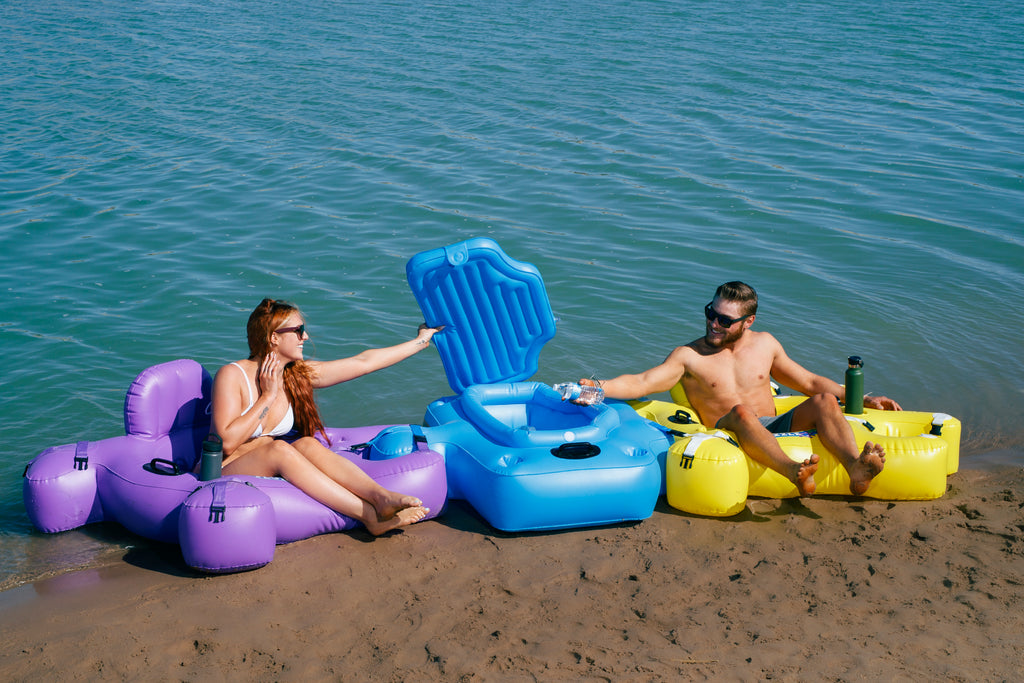 Woman and Man in bathing suits floating in Purple and Yellow Fluzzle Tubes with interlocking floating cooler.  Easy to use and no ropes to stay connected on the water.  Keeps drinks cold while you float.  Fluzzle Tube Buddy Bundle with  floating cooler. Expandable cup holders. Inflatable back rests and mesh bottoms. 